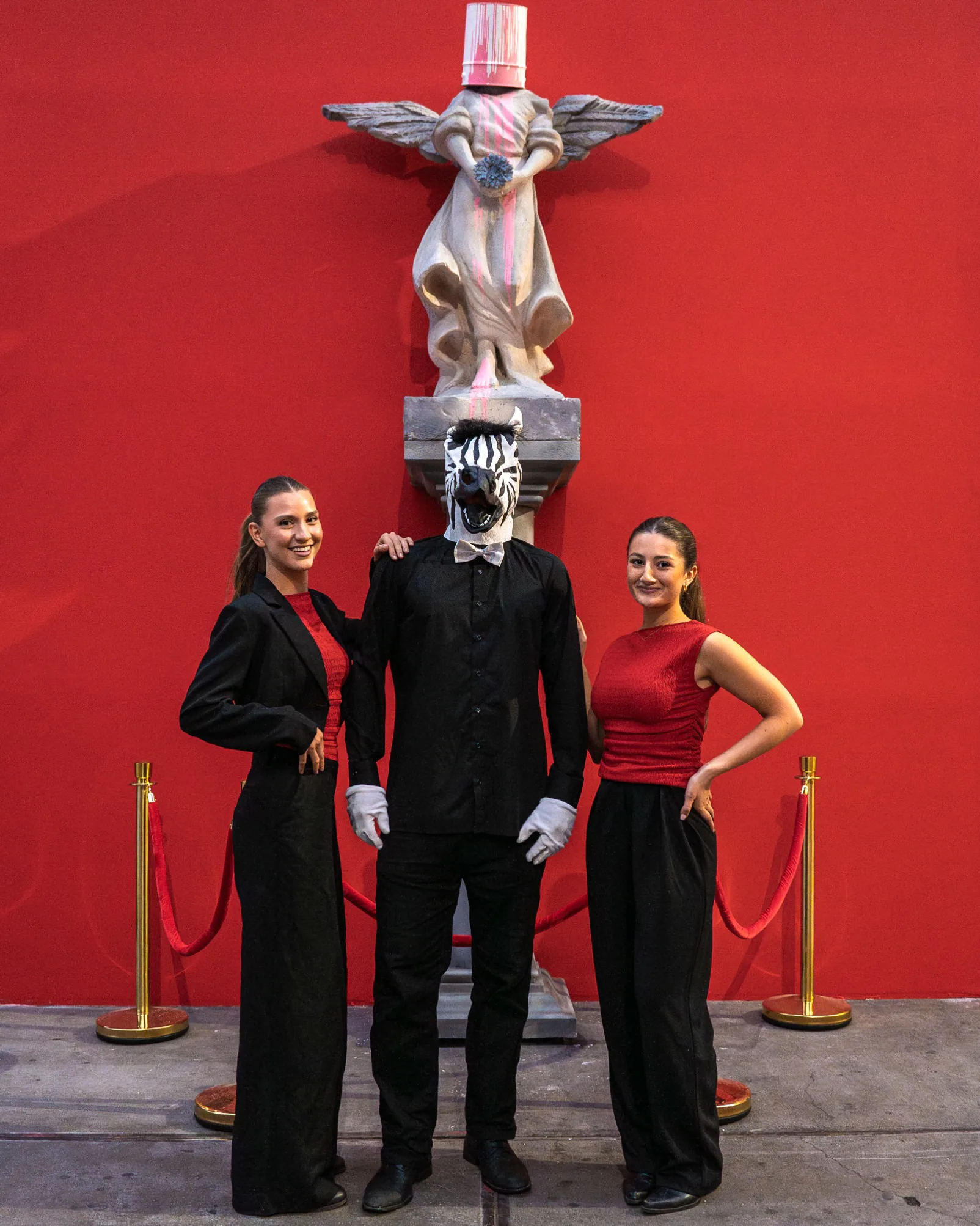 Two High Hospitality hostesses with a performer at The Art of Banksy