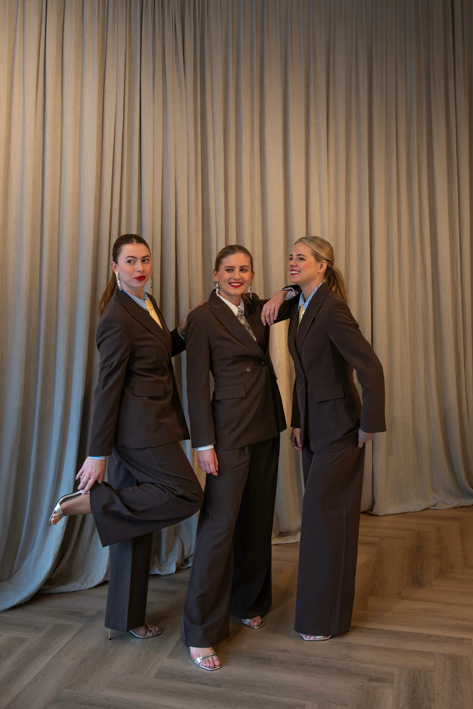 Three High Hospitality team members in tailored brown suits